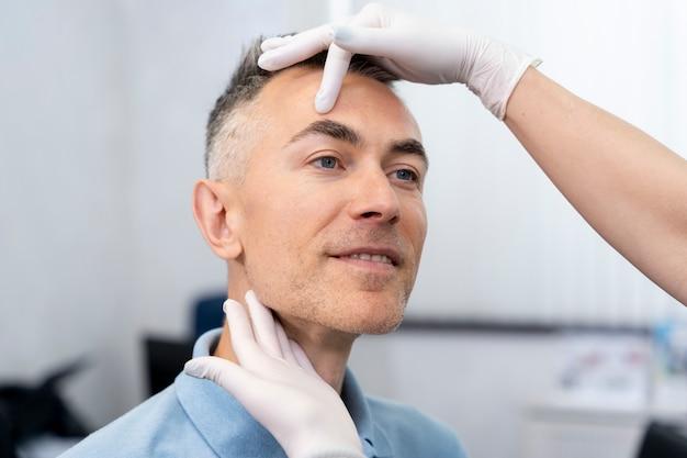 Man receiving a dermatological examination on his face