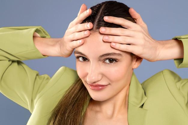 woman in green blouse smiling and touching her forehead