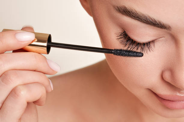 Woman applying mascara to eyelashes