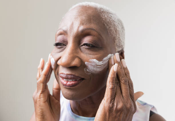 Senior woman applying moisturizing cream on her face