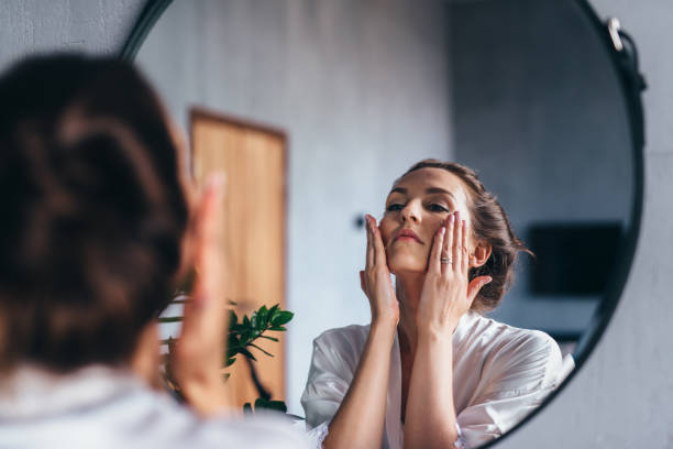 Woman applying skincare looking in mirror