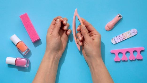 Manicure process with hands, nail file, and nail polish on a blue background